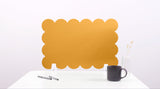 Yellow scalloped placemat on a white surface with a black mug and pen.
