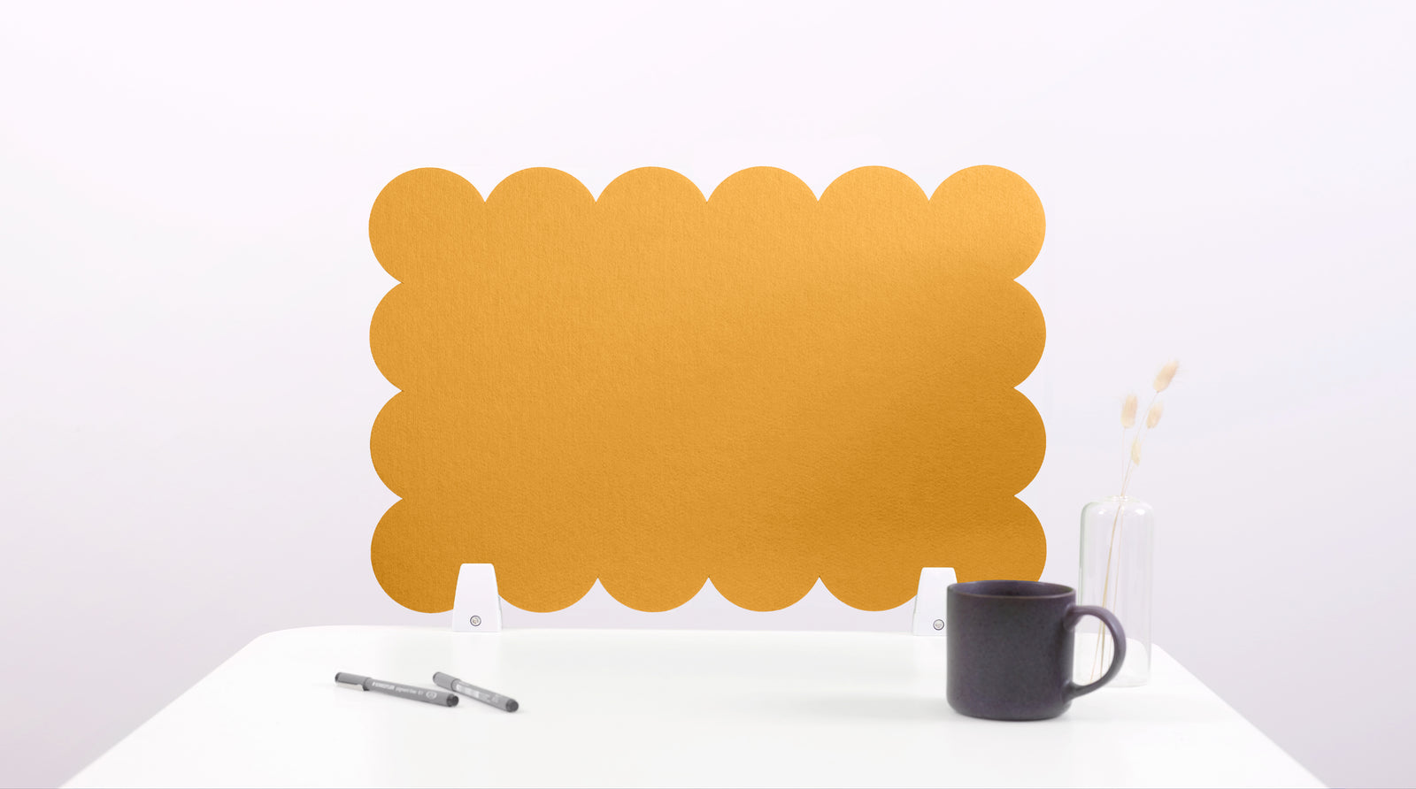 Yellow scalloped placemat on a white surface with a black mug and pen.