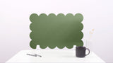 Green scalloped screen on a white surface with a black mug and pen.