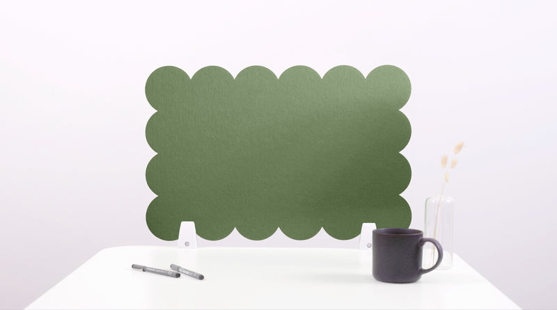 Green scalloped screen on a white surface with a black mug and pen.