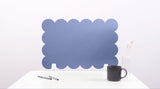 Blue scalloped headboard on a white background with a black mug and pen.