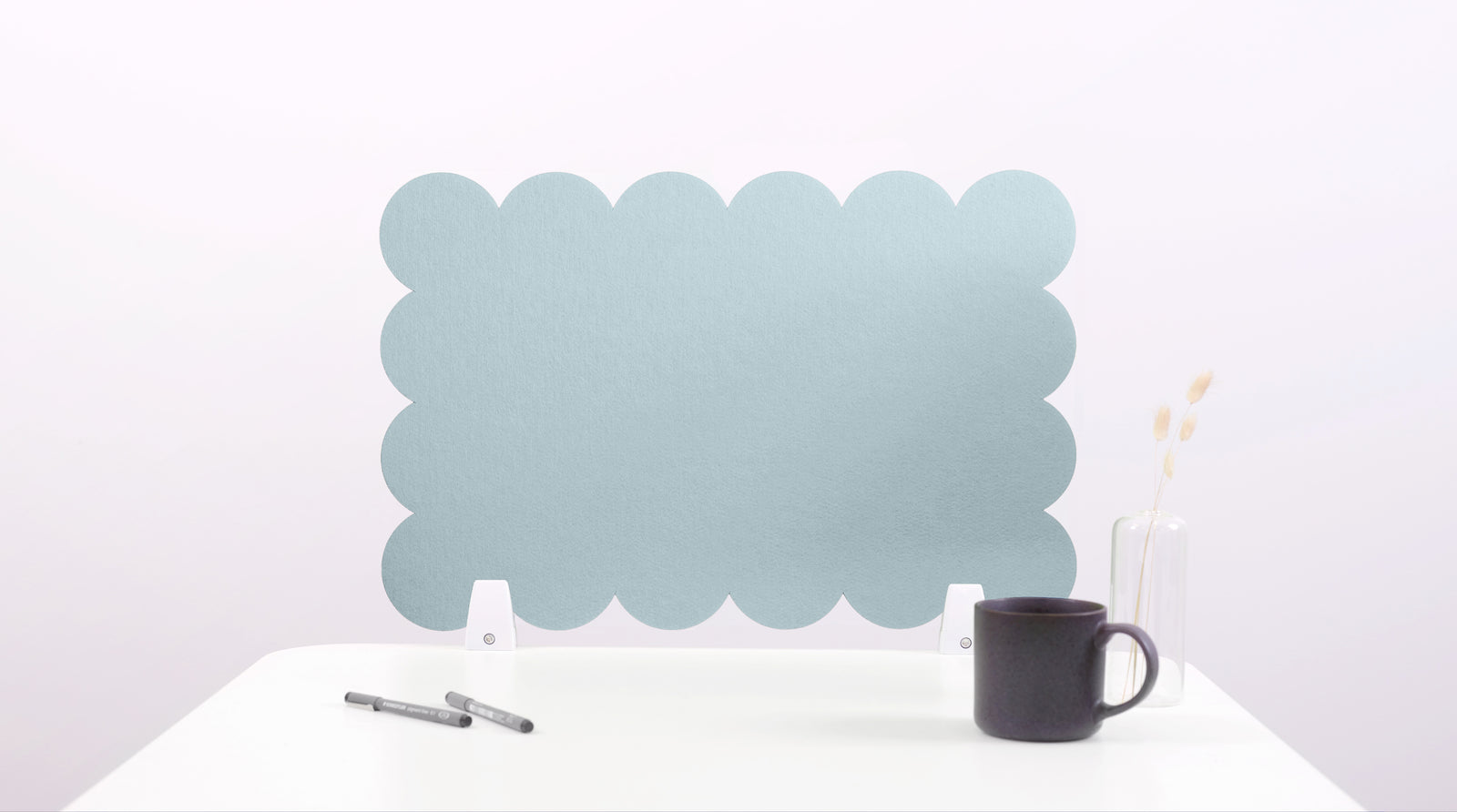 Light blue scalloped headboard on a white background with a black mug and pen.
