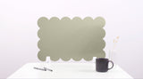 Green scalloped screen on a white surface with a black mug and pen.