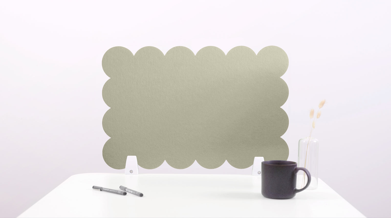 Green scalloped screen on a white surface with a black mug and pen.