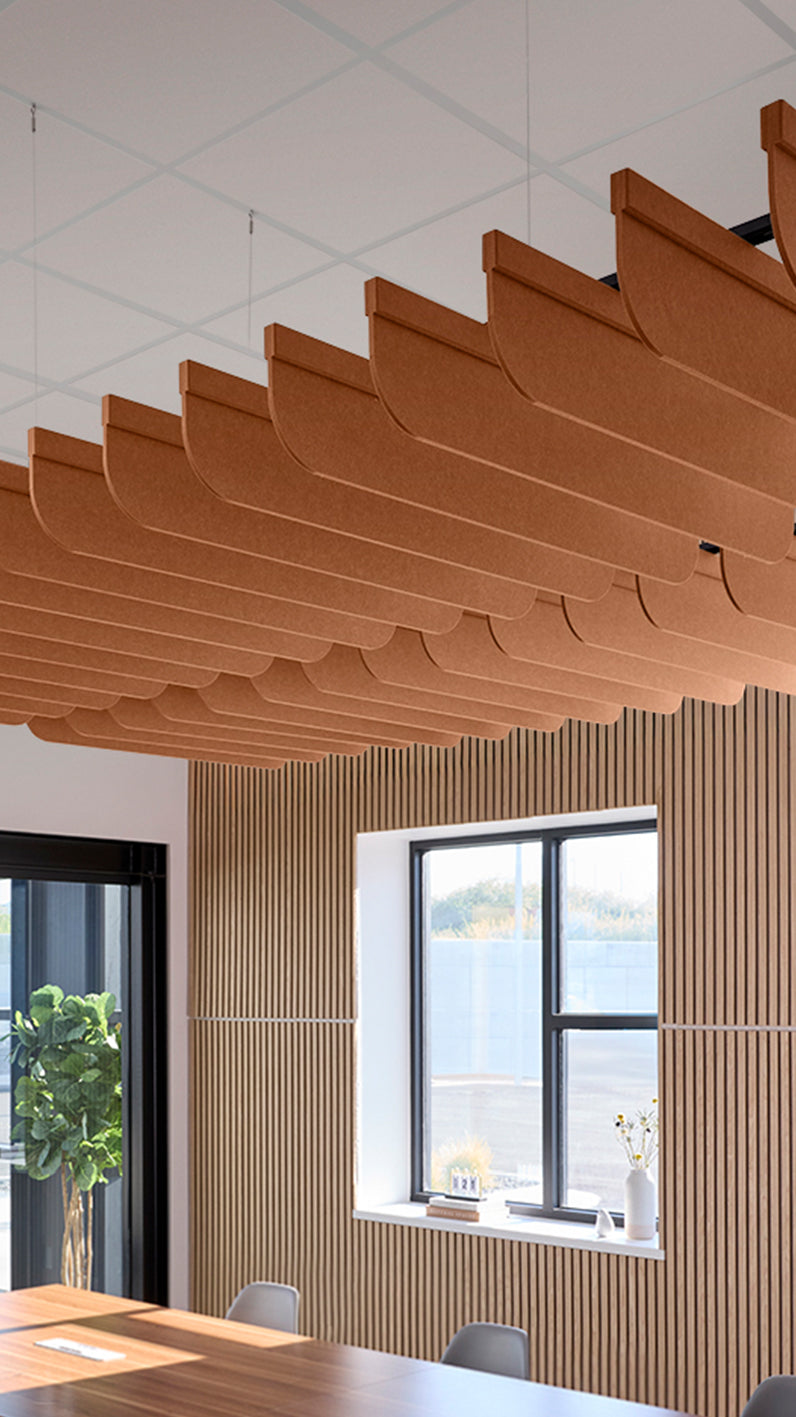 Dark orange acoustic ceiling blade baffles suspended from the ceiling, installed in a conference room. Felt Right's acoustic blade baffles absorb 65% of sound waves, making office spaces quieter and feel more calm.