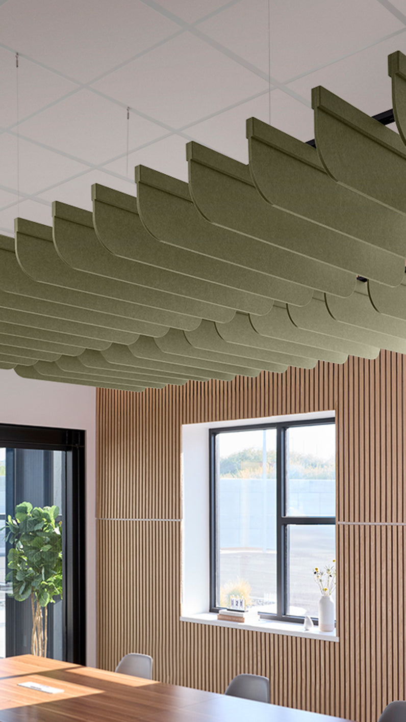 Green acoustic ceiling blade baffles suspended from the ceiling, installed in a conference room. Felt Right's acoustic blade baffles absorb 65% of sound waves, making office spaces quieter and feel more calm.