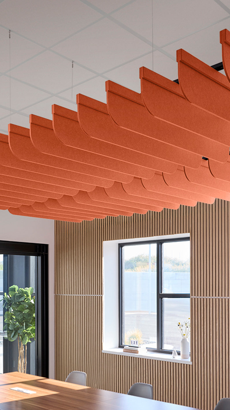 Orange acoustic ceiling blade baffles suspended from the ceiling, installed in a conference room. Felt Right's acoustic blade baffles absorb 65% of sound waves, making office spaces quieter and feel more calm.