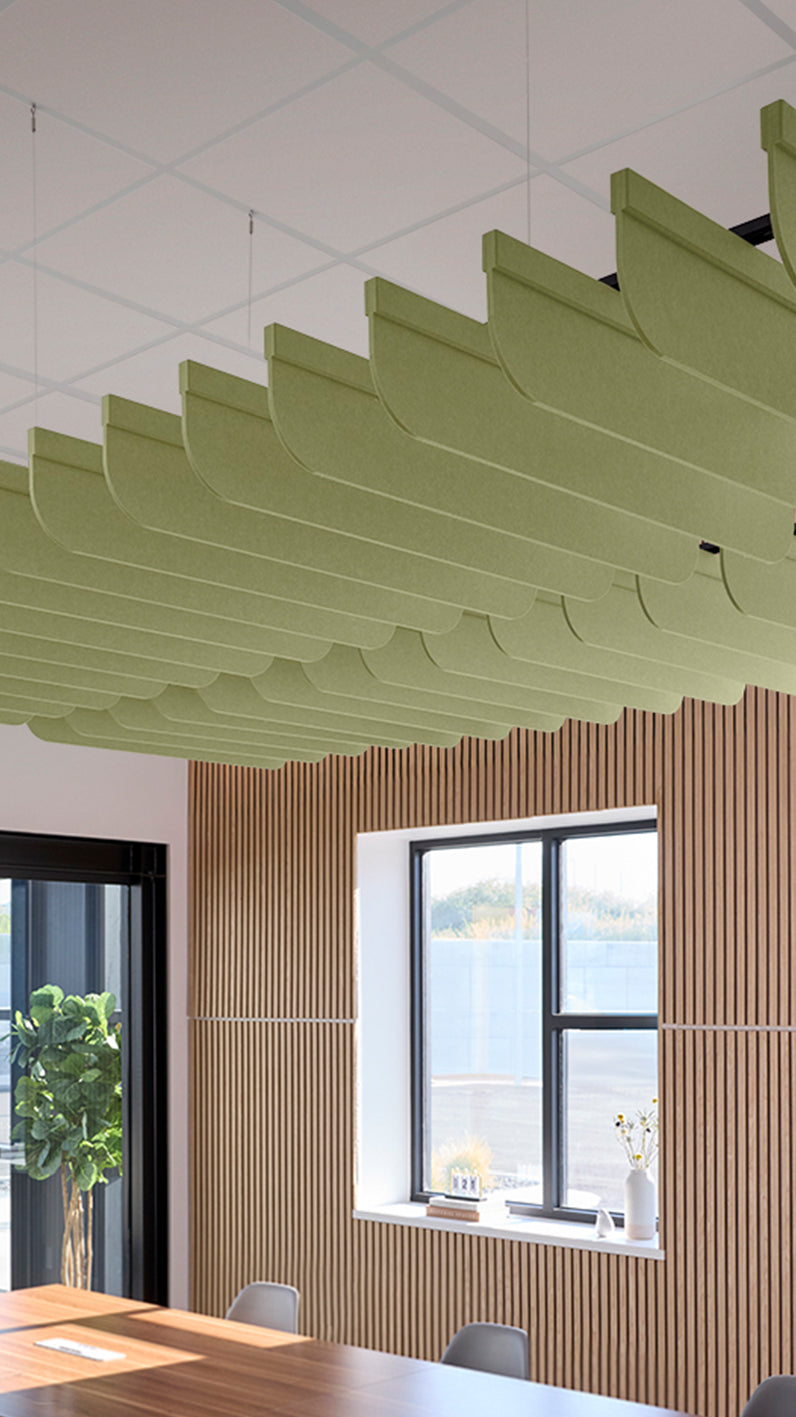 Light green acoustic ceiling blade baffles suspended from the ceiling, installed in a conference room. Felt Right's acoustic blade baffles absorb 65% of sound waves, making office spaces quieter and feel more calm.