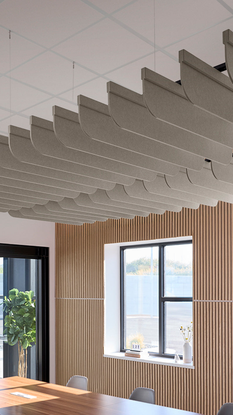 Light brownish-grey acoustic ceiling blade baffles suspended from the ceiling, installed in a conference room. Felt Right's acoustic blade baffles absorb 65% of sound waves, making office spaces quieter and feel more calm.