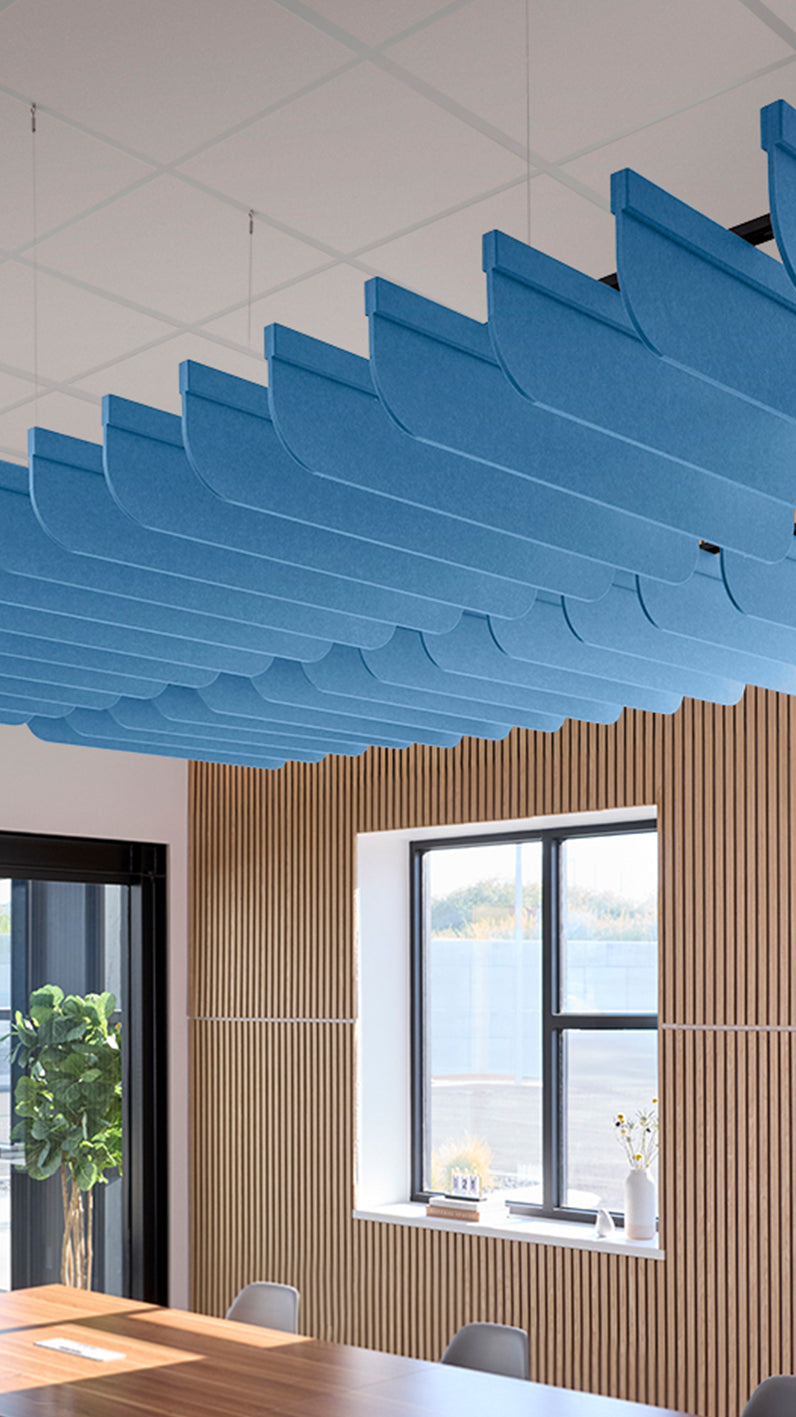 Bright blue acoustic ceiling blade baffles suspended from the ceiling, installed in a conference room. Felt Right's acoustic blade baffles absorb 65% of sound waves, making office spaces quieter and feel more calm.