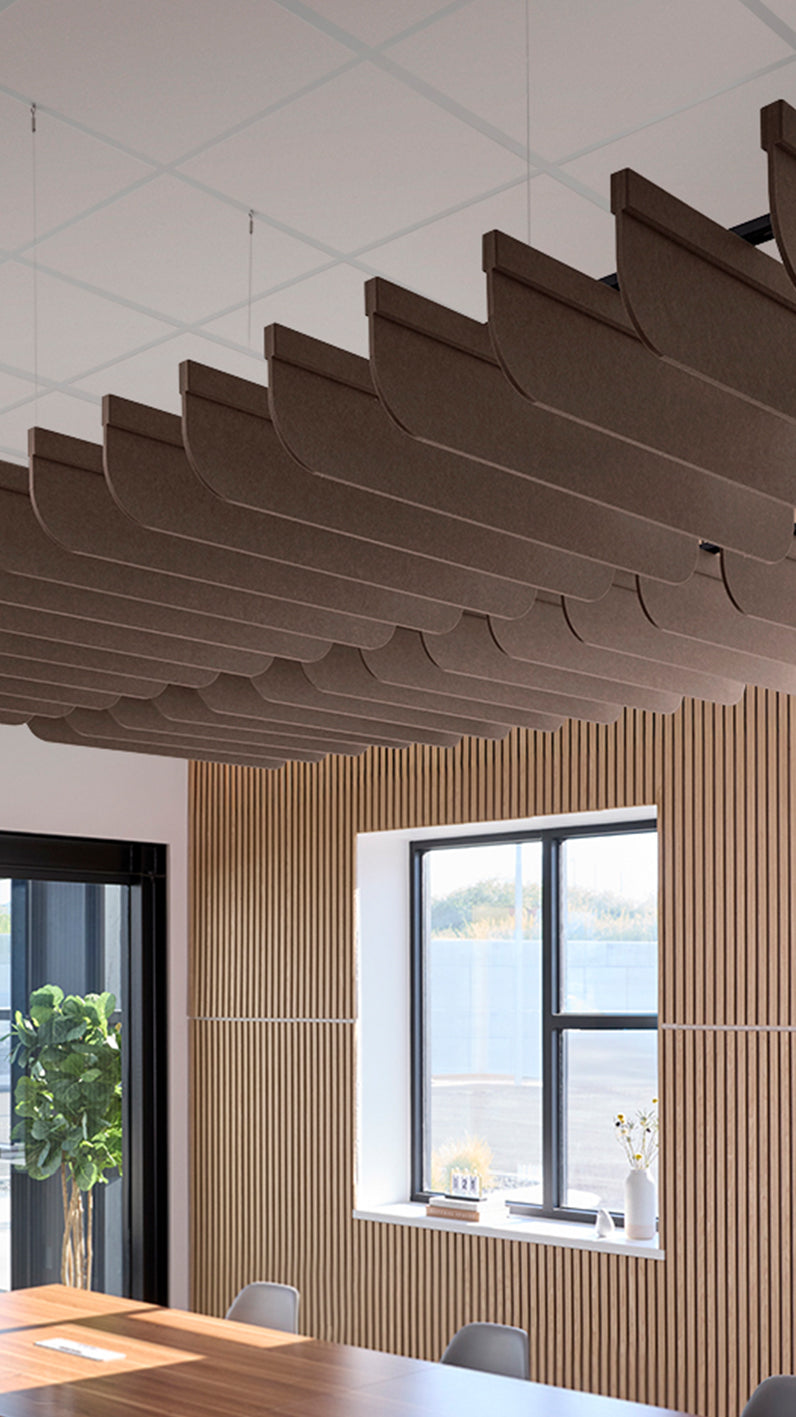 Brown acoustic ceiling blade baffles suspended from the ceiling, installed in a conference room. Felt Right's acoustic blade baffles absorb 65% of sound waves, making office spaces quieter and feel more calm.