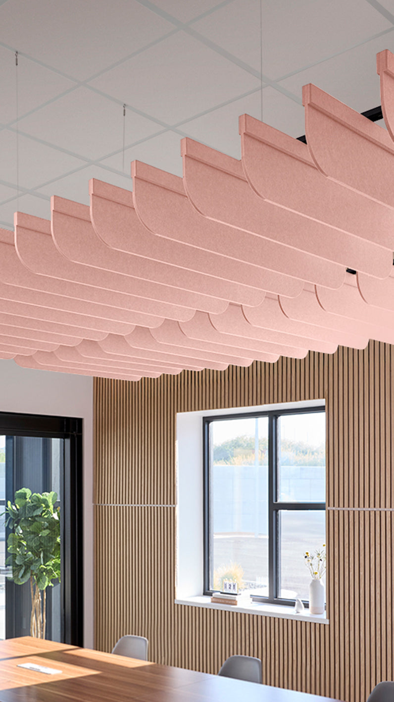 Soft pink acoustic ceiling blade baffles suspended from the ceiling, installed in a conference room. Felt Right's acoustic blade baffles absorb 65% of sound waves, making office spaces quieter and feel more calm.