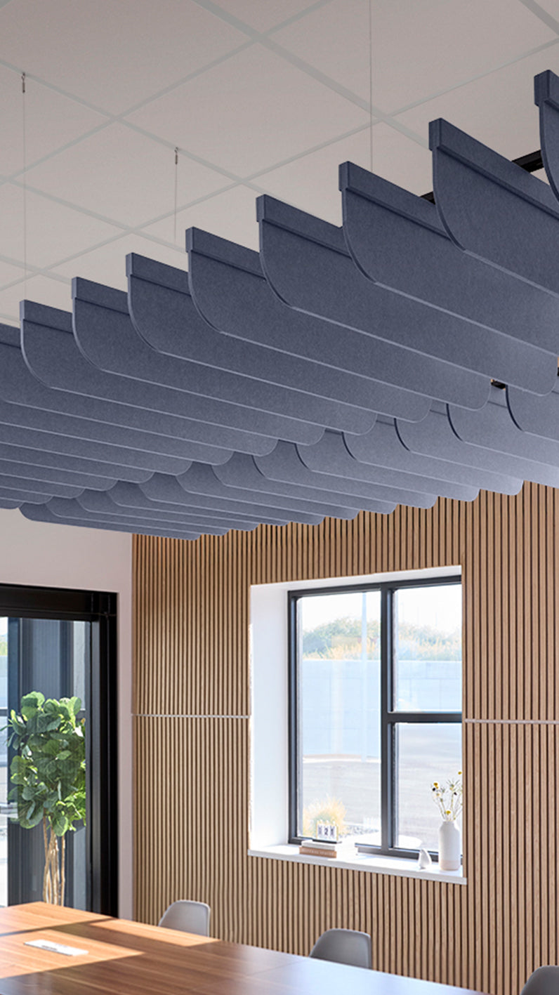 Indigo blue acoustic ceiling blade baffles suspended from the ceiling, installed in a conference room. Felt Right's acoustic blade baffles absorb 65% of sound waves, making office spaces quieter and feel more calm.
