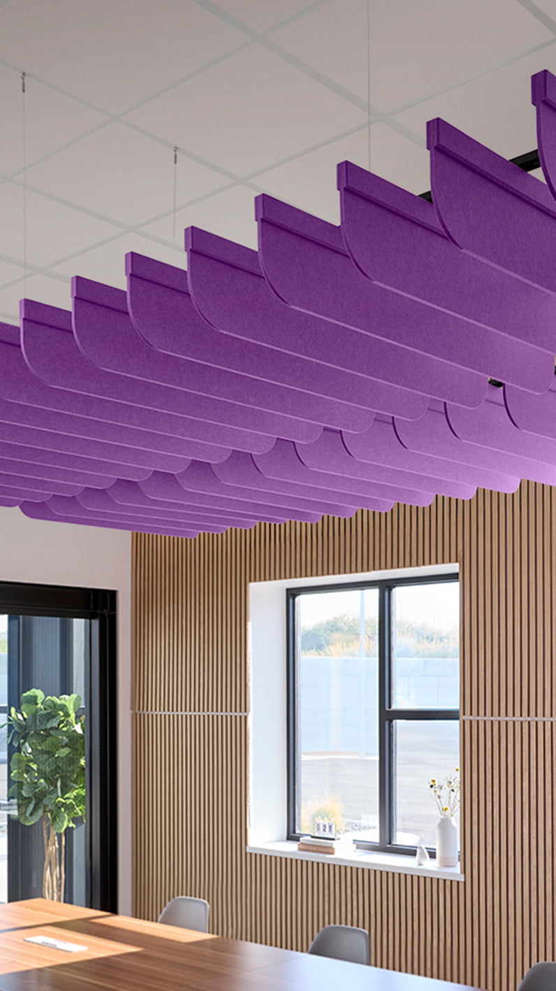 Purple acoustic ceiling blade baffles suspended from the ceiling, installed in a conference room. Felt Right's acoustic blade baffles absorb 65% of sound waves, making office spaces quieter and feel more calm.