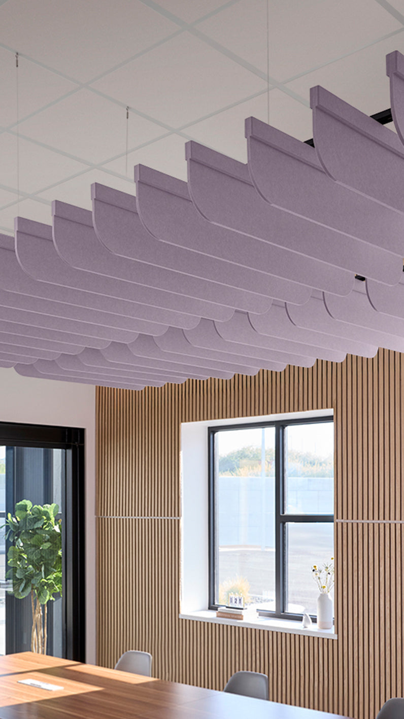 Light purple acoustic ceiling blade baffles suspended from the ceiling, installed in a conference room. Felt Right's acoustic blade baffles absorb 65% of sound waves, making office spaces quieter and feel more calm.