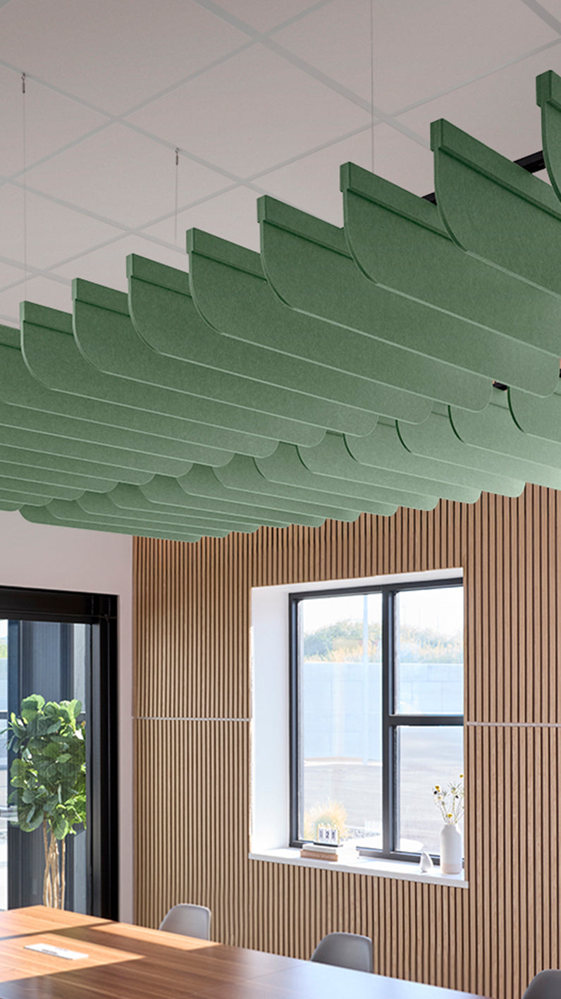 Green acoustic ceiling blade baffles suspended from the ceiling, installed in a conference room. Felt Right's acoustic blade baffles absorb 65% of sound waves, making office spaces quieter and feel more calm.