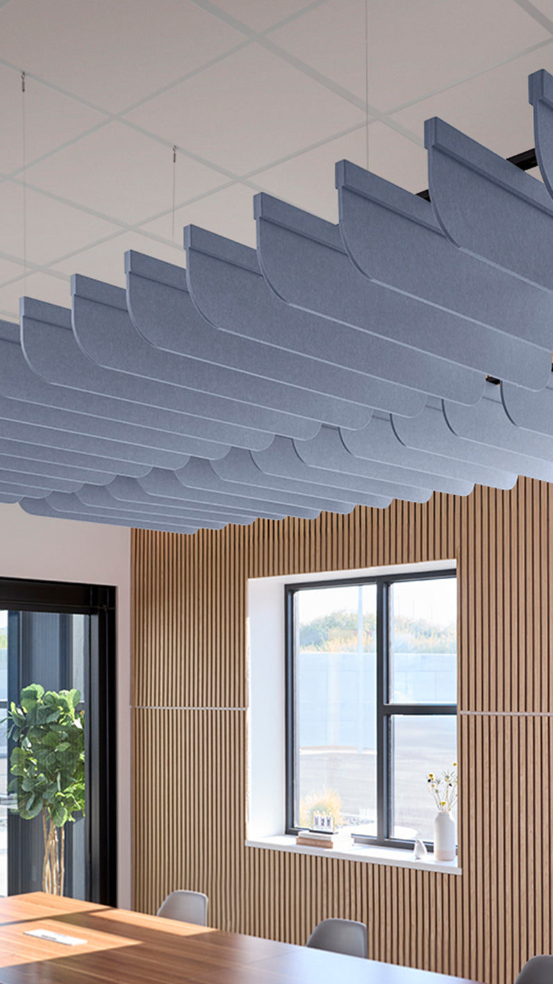 Purplish-blue acoustic ceiling blade baffles suspended from the ceiling, installed in a conference room. Felt Right's acoustic blade baffles absorb 65% of sound waves, making office spaces quieter and feel more calm.
