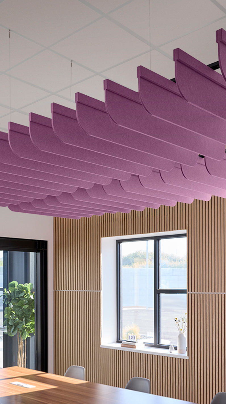 Reddish-purple acoustic ceiling blade baffles suspended from the ceiling, installed in a conference room. Felt Right's acoustic blade baffles absorb 65% of sound waves, making office spaces quieter and feel more calm.