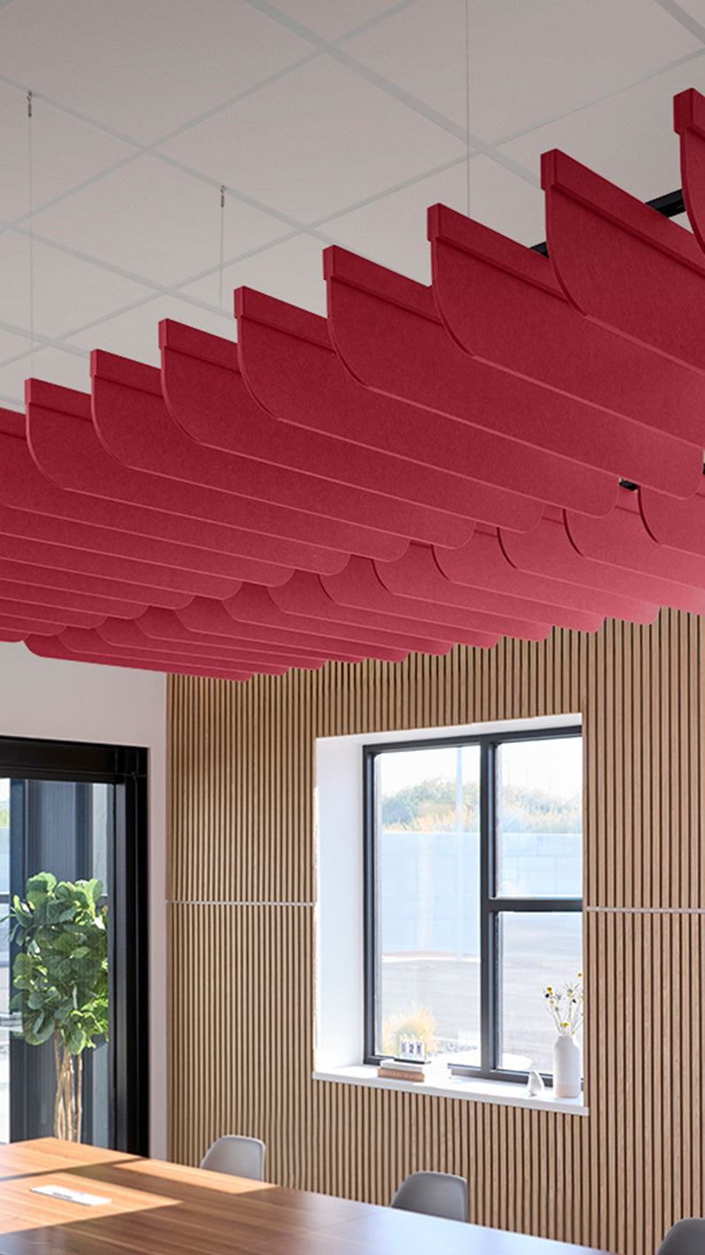 Red acoustic ceiling blade baffles suspended from the ceiling, installed in a conference room. Felt Right's acoustic blade baffles absorb 65% of sound waves, making office spaces quieter and feel more calm.