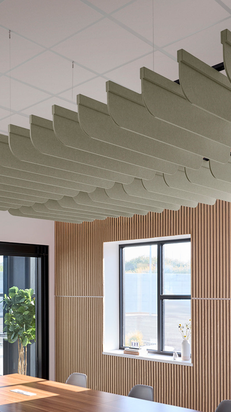 Soft green acoustic ceiling blade baffles suspended from the ceiling, installed in a conference room. Felt Right's acoustic blade baffles absorb 65% of sound waves, making office spaces quieter and feel more calm.