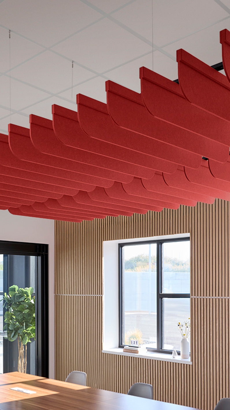 Bright red acoustic ceiling blade baffles suspended from the ceiling, installed in a conference room. Felt Right's acoustic blade baffles absorb 65% of sound waves, making office spaces quieter and feel more calm.