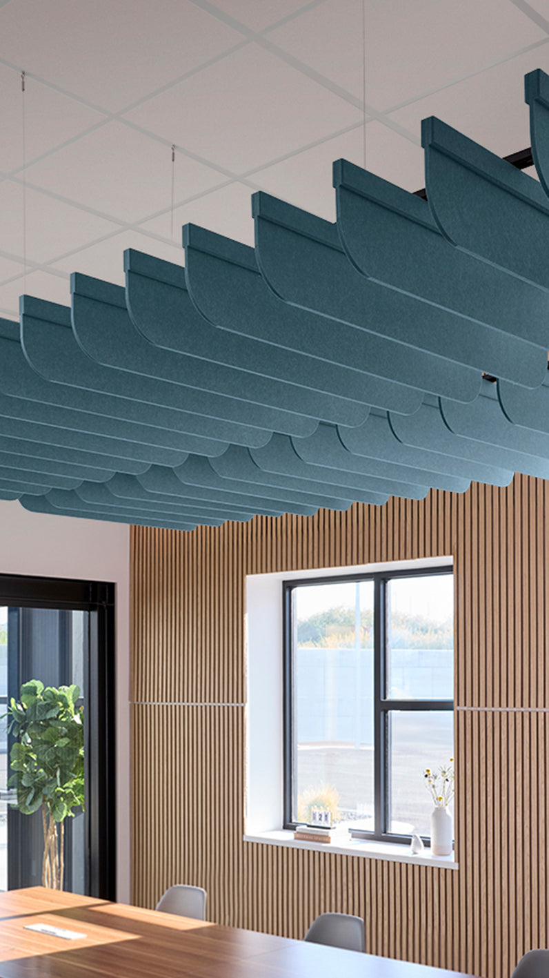 Teal blue acoustic ceiling blade baffles suspended from the ceiling, installed in a conference room. Felt Right's acoustic blade baffles absorb 65% of sound waves, making office spaces quieter and feel more calm.