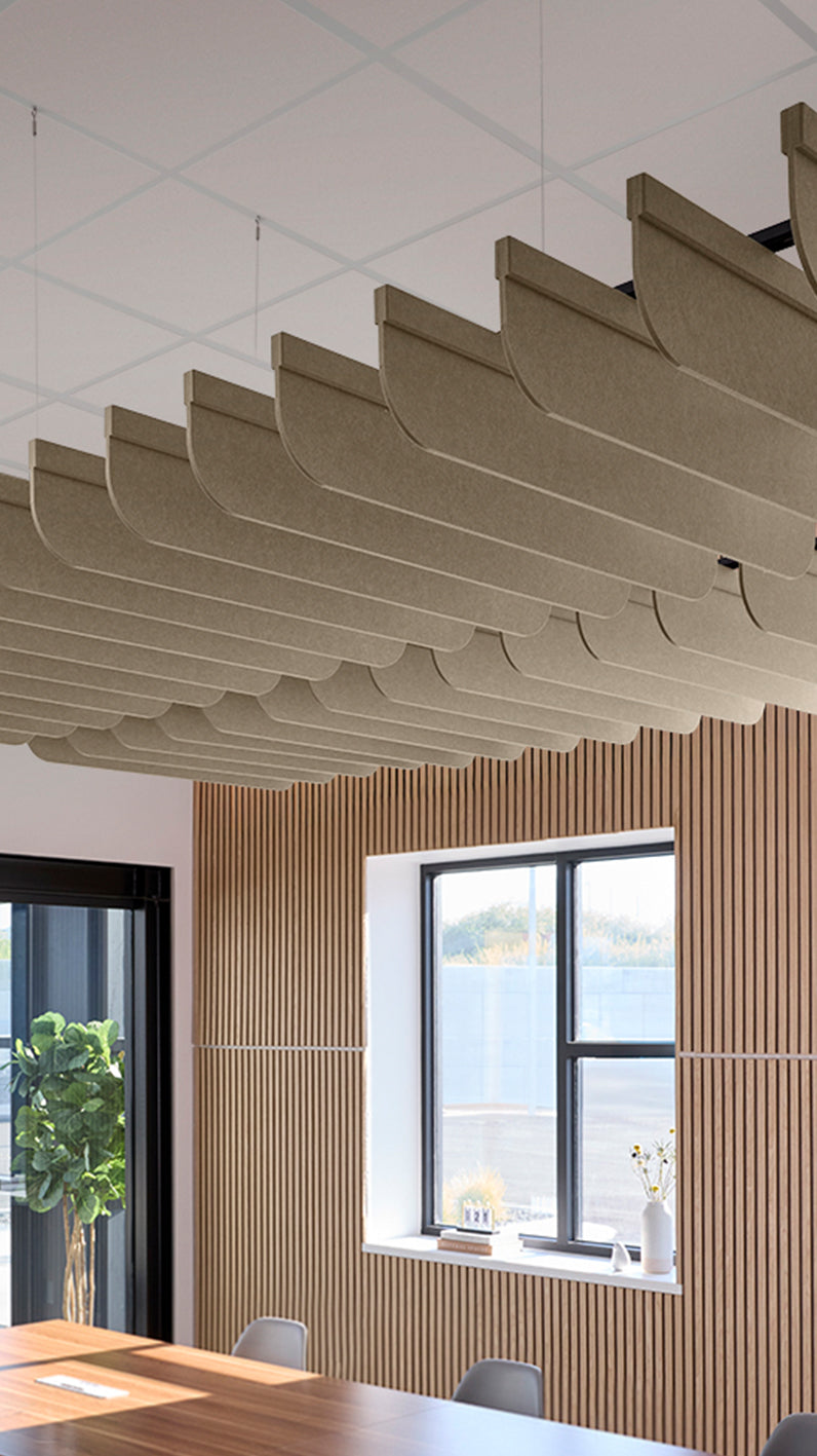 Light brown acoustic ceiling blade baffles suspended from the ceiling, installed in a conference room. Felt Right's acoustic blade baffles absorb 65% of sound waves, making office spaces quieter and feel more calm.