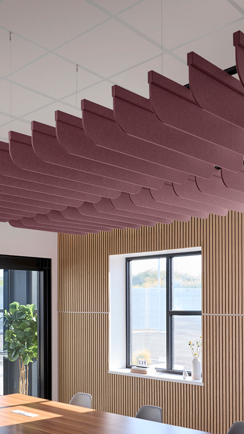 Deep reddish-purple acoustic ceiling blade baffles suspended from the ceiling, installed in a conference room. Felt Right's acoustic blade baffles absorb 65% of sound waves, making office spaces quieter and feel more calm.