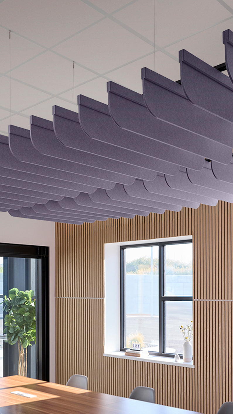 Soft violet acoustic ceiling blade baffles suspended from the ceiling, installed in a conference room. Felt Right's acoustic blade baffles absorb 65% of sound waves, making office spaces quieter and feel more calm.
