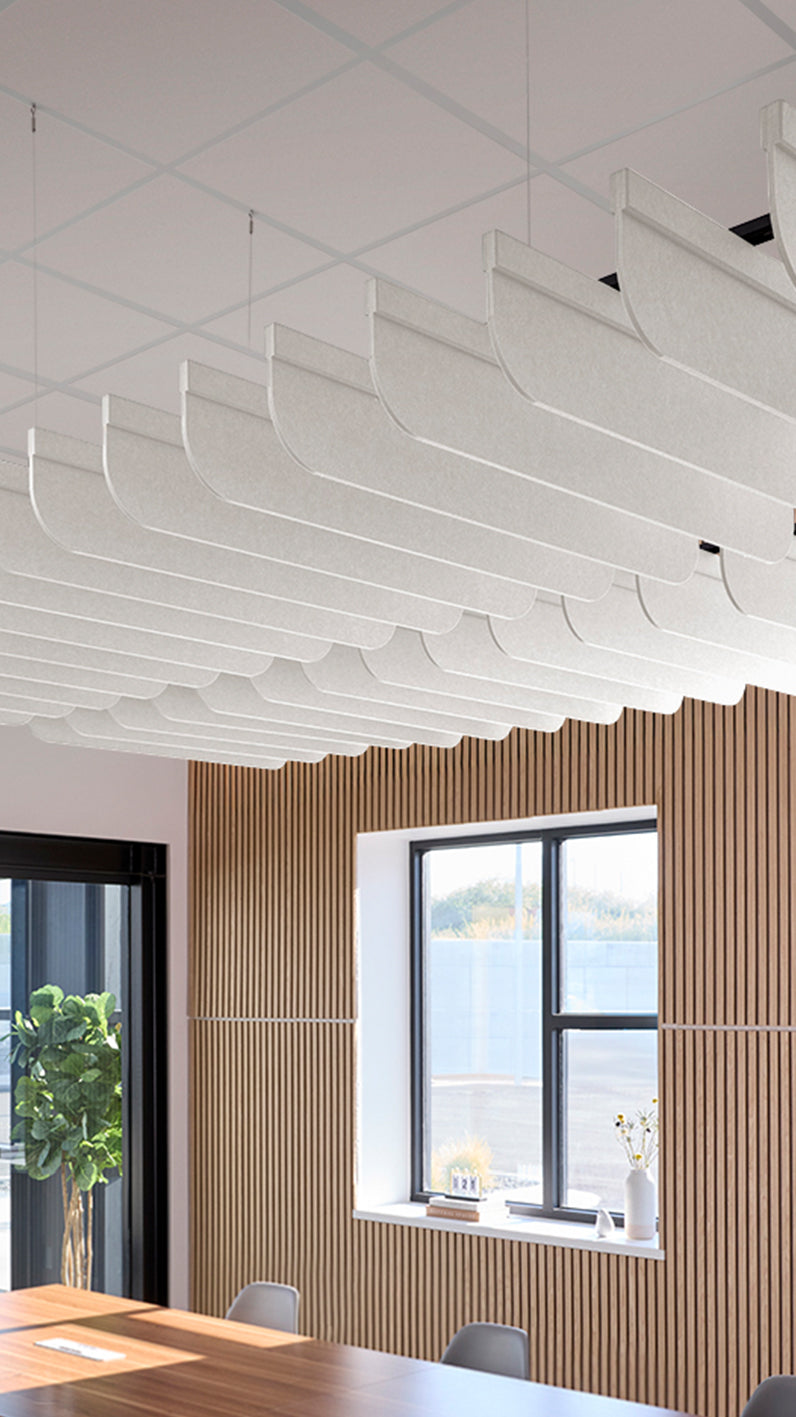 White acoustic ceiling blade baffles suspended from the ceiling, installed in a conference room. Felt Right's acoustic blade baffles absorb 65% of sound waves, making office spaces quieter and feel more calm.