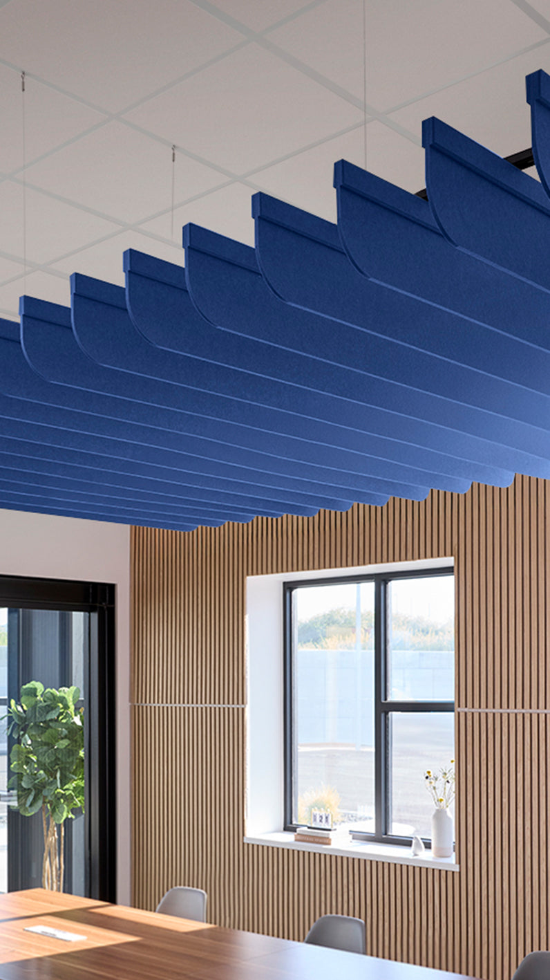 Blue acoustic ceiling blade baffles suspended from the ceiling, installed in a conference room. Felt Right's acoustic blade baffles absorb 65% of sound waves, making office spaces quieter and feel more calm.