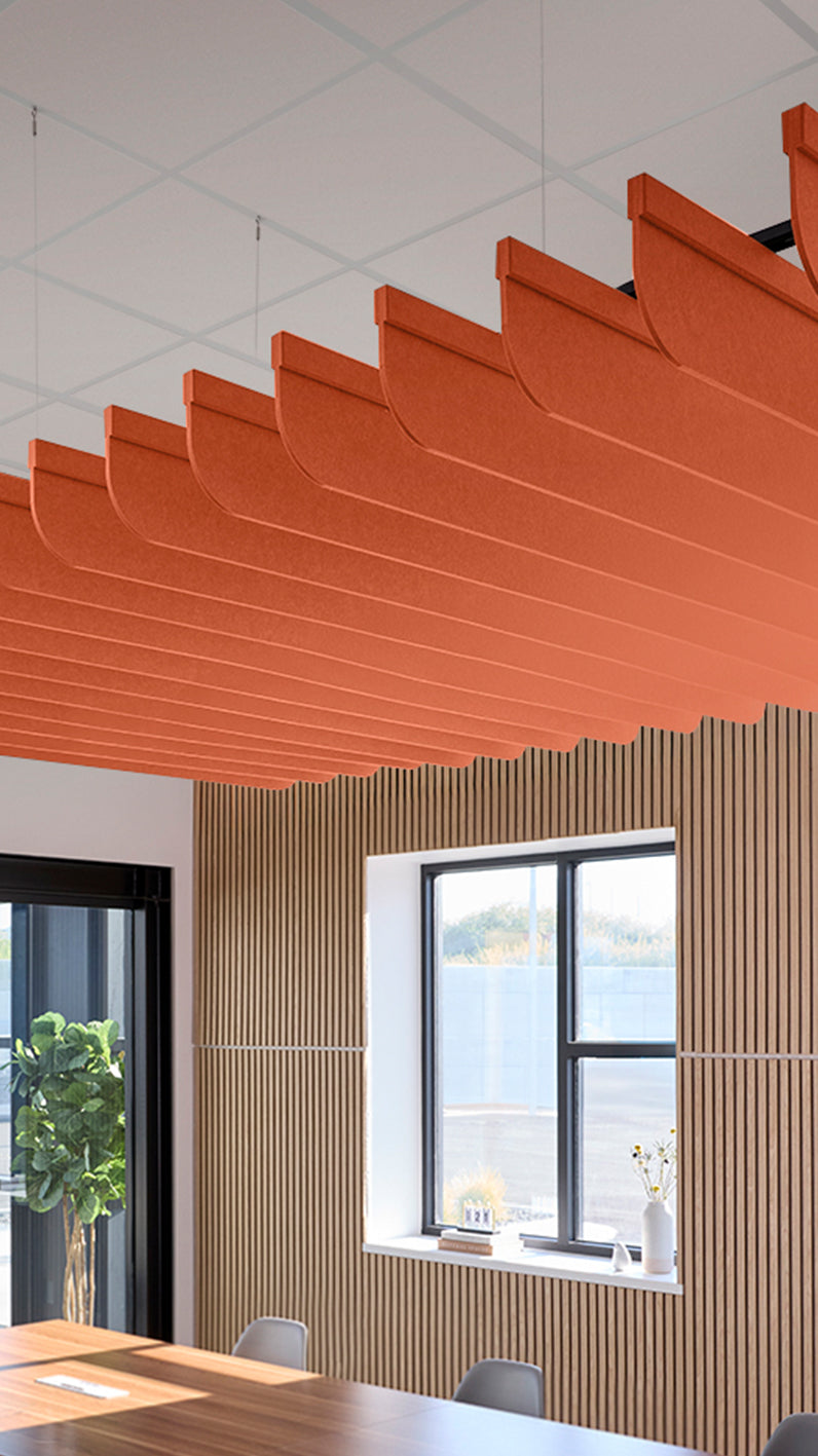 Orange acoustic ceiling blade baffles suspended from the ceiling, installed in a conference room. Felt Right's acoustic blade baffles absorb 65% of sound waves, making office spaces quieter and feel more calm.