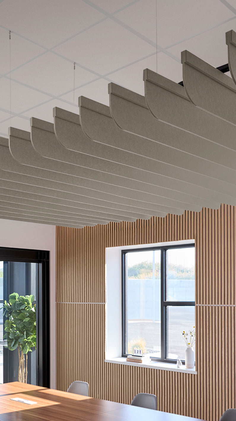 Light brownish-grey acoustic ceiling blade baffles suspended from the ceiling, installed in a conference room. Felt Right's acoustic blade baffles absorb 65% of sound waves, making office spaces quieter and feel more calm.