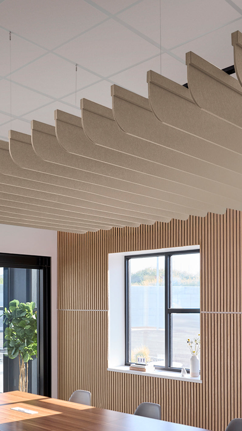 Creamy beige acoustic ceiling blade baffles suspended from the ceiling, installed in a conference room. Felt Right's acoustic blade baffles absorb 65% of sound waves, making office spaces quieter and feel more calm.