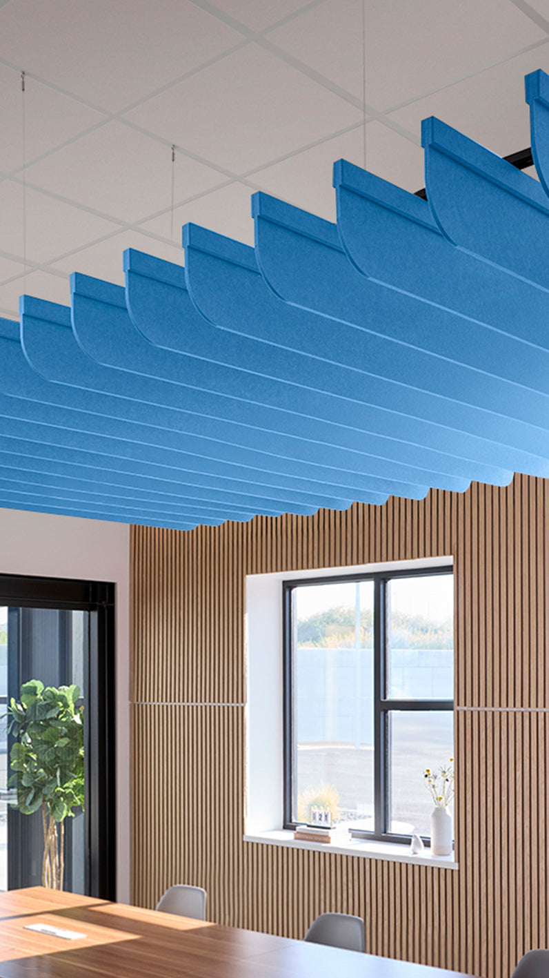 Bright blue acoustic ceiling blade baffles suspended from the ceiling, installed in a conference room. Felt Right's acoustic blade baffles absorb 65% of sound waves, making office spaces quieter and feel more calm.