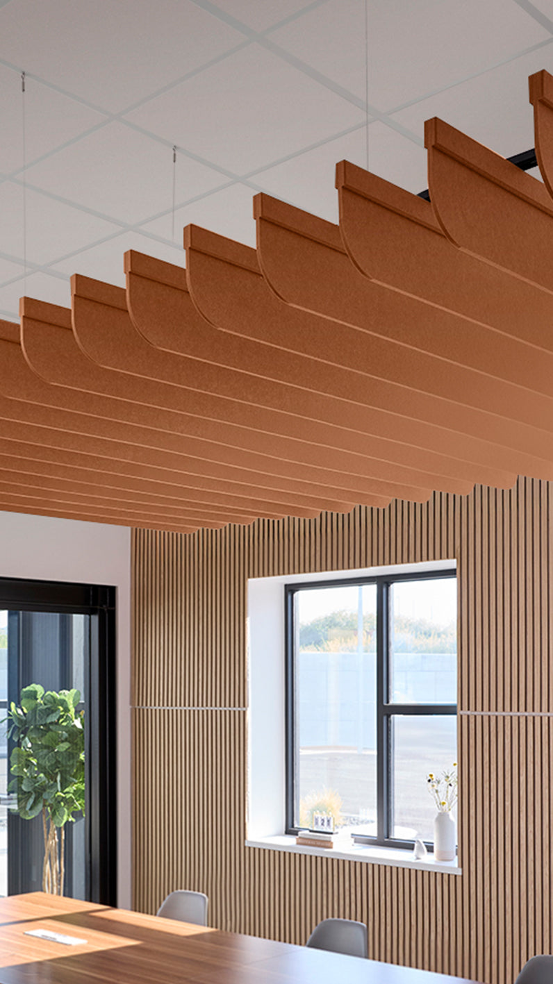 Dark orange acoustic ceiling blade baffles suspended from the ceiling, installed in a conference room. Felt Right's acoustic blade baffles absorb 65% of sound waves, making office spaces quieter and feel more calm.
