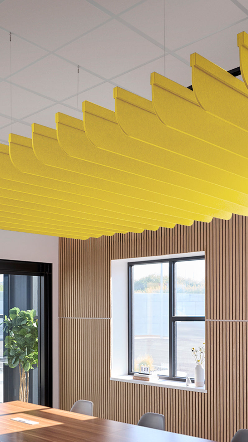 Yellow acoustic ceiling blade baffles suspended from the ceiling, installed in a conference room. Felt Right's acoustic blade baffles absorb 65% of sound waves, making office spaces quieter and feel more calm.