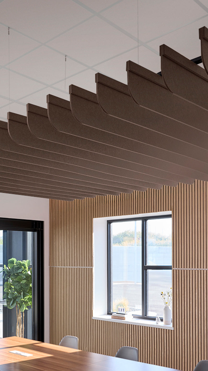Brown acoustic ceiling blade baffles suspended from the ceiling, installed in a conference room. Felt Right's acoustic blade baffles absorb 65% of sound waves, making office spaces quieter and feel more calm.