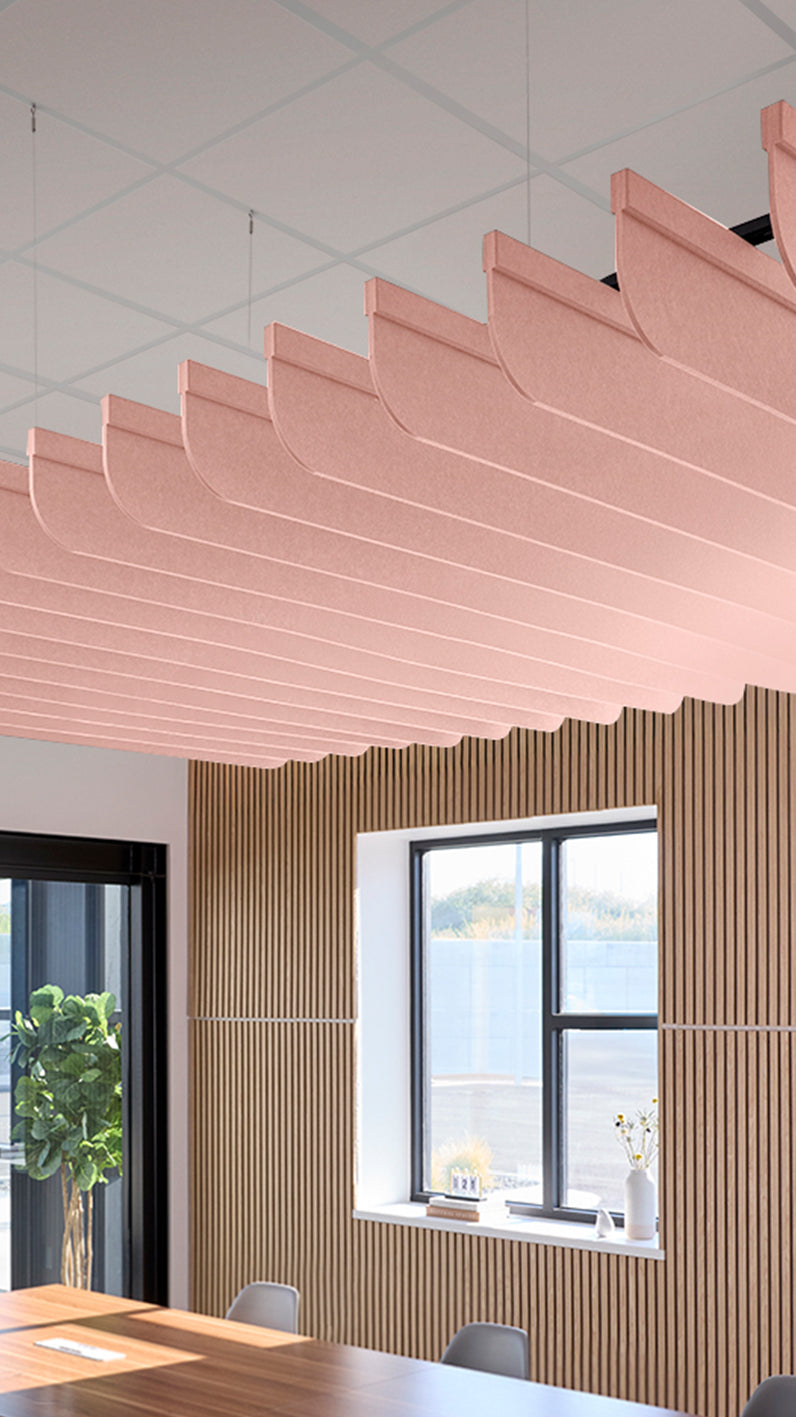 Soft pink acoustic ceiling blade baffles suspended from the ceiling, installed in a conference room. Felt Right's acoustic blade baffles absorb 65% of sound waves, making office spaces quieter and feel more calm.