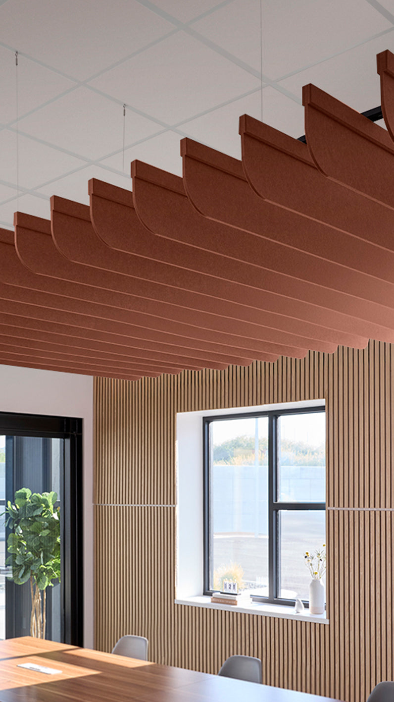 Reddish-brown acoustic ceiling blade baffles suspended from the ceiling, installed in a conference room. Felt Right's acoustic blade baffles absorb 65% of sound waves, making office spaces quieter and feel more calm.