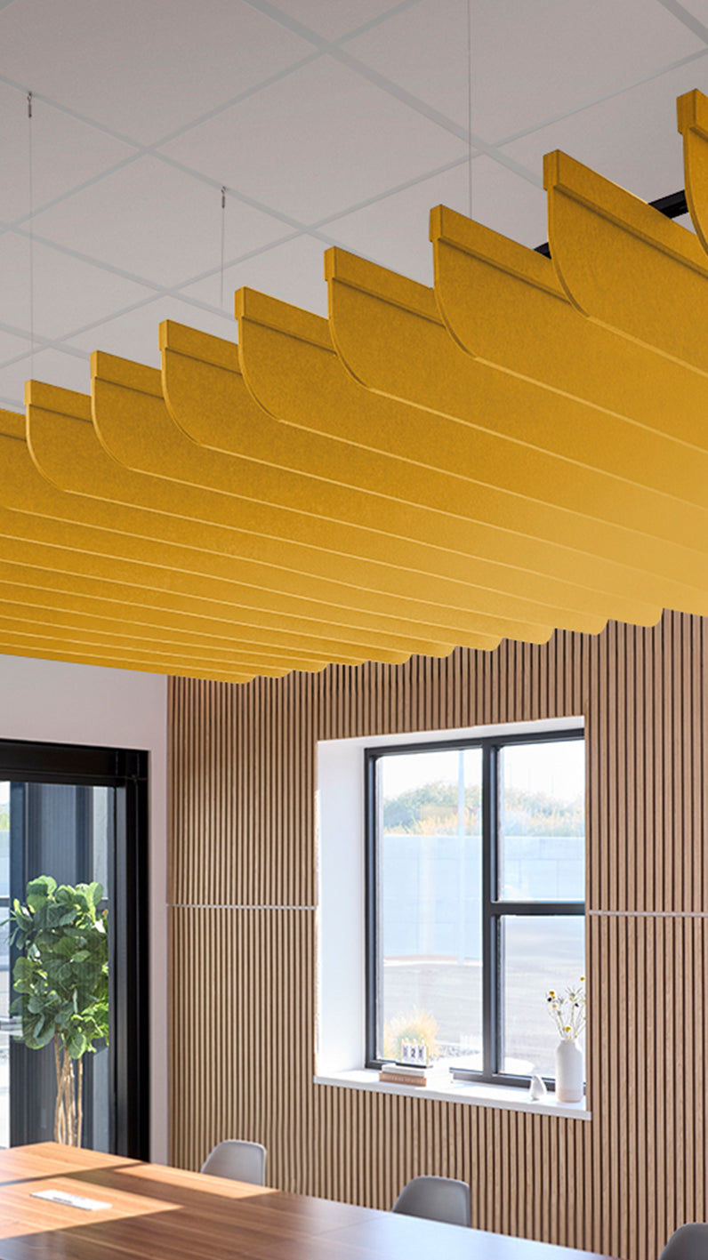 Dark yellow acoustic ceiling blade baffles suspended from the ceiling, installed in a conference room. Felt Right's acoustic blade baffles absorb 65% of sound waves, making office spaces quieter and feel more calm.