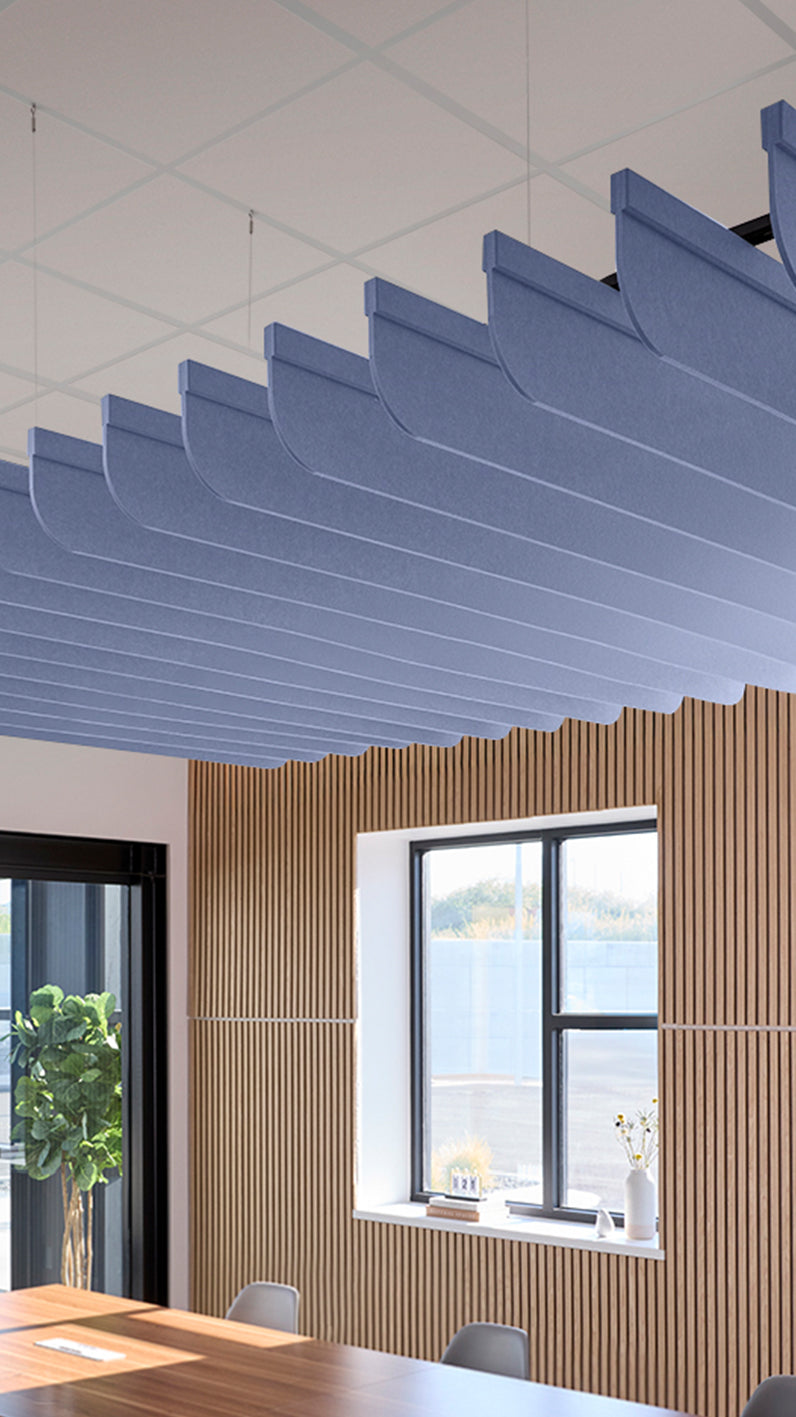 Purplish-blue acoustic ceiling blade baffles suspended from the ceiling, installed in a conference room. Felt Right's acoustic blade baffles absorb 65% of sound waves, making office spaces quieter and feel more calm.