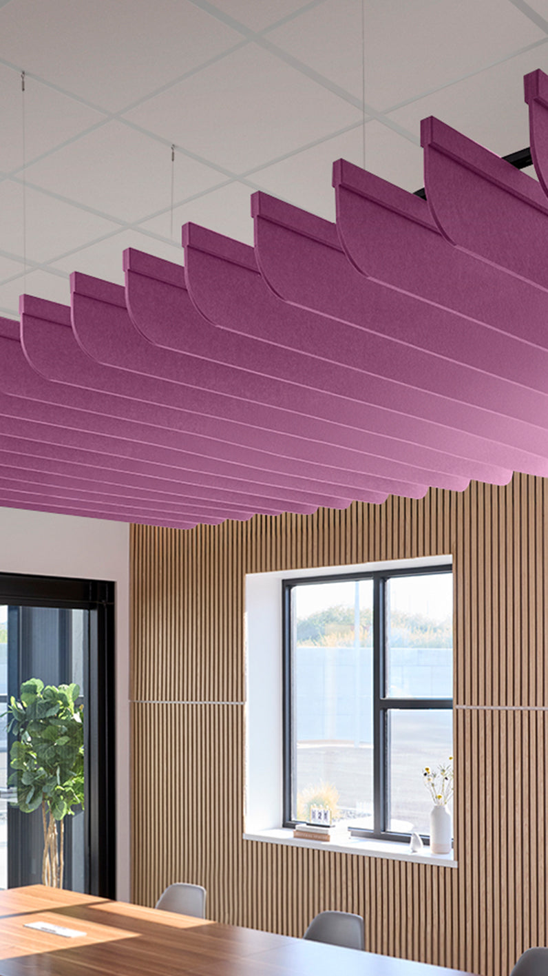 Reddish-purple acoustic ceiling blade baffles suspended from the ceiling, installed in a conference room. Felt Right's acoustic blade baffles absorb 65% of sound waves, making office spaces quieter and feel more calm.