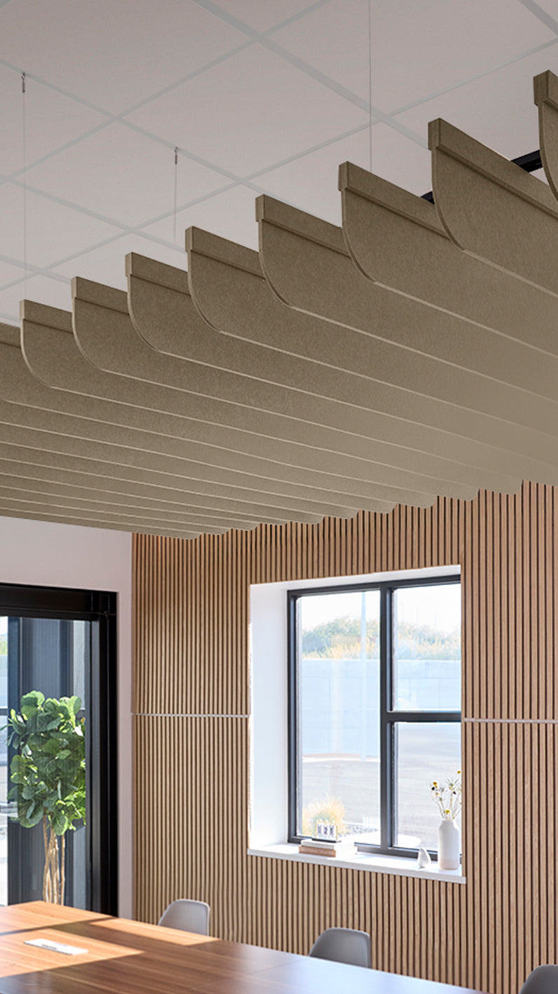 Light brown acoustic ceiling blade baffles suspended from the ceiling, installed in a conference room. Felt Right's acoustic blade baffles absorb 65% of sound waves, making office spaces quieter and feel more calm.
