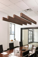 Four brown wood grain acoustic beams suspended from ceiling above conference table in office space.