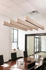 Four light wood grain acoustic beams suspended from ceiling above conference table in office interior.