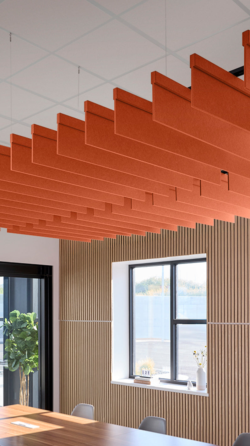 Orange acoustic ceiling blade baffles suspended from the ceiling, installed in a conference room. Felt Right's acoustic blade baffles absorb 65% of sound waves, making office spaces quieter and feel more calm.