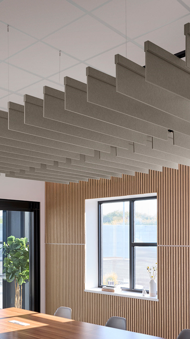Light brownish-grey acoustic ceiling blade baffles suspended from the ceiling, installed in a conference room. Felt Right's acoustic blade baffles absorb 65% of sound waves, making office spaces quieter and feel more calm.