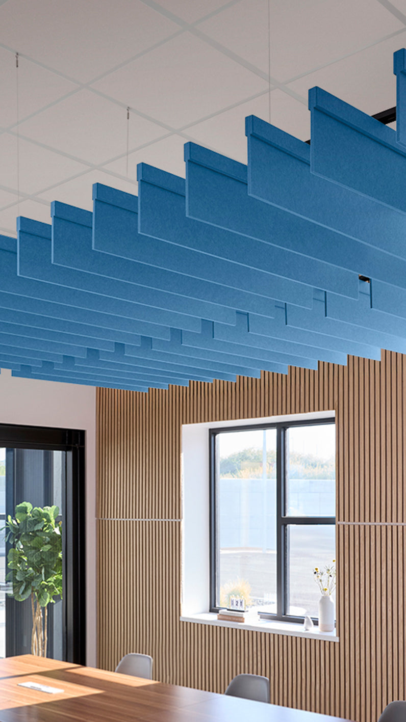 Bright blue acoustic ceiling blade baffles suspended from the ceiling, installed in a conference room. Felt Right's acoustic blade baffles absorb 65% of sound waves, making office spaces quieter and feel more calm.