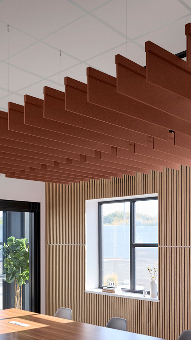 Reddish-brown acoustic ceiling blade baffles suspended from the ceiling, installed in a conference room. Felt Right's acoustic blade baffles absorb 65% of sound waves, making office spaces quieter and feel more calm.